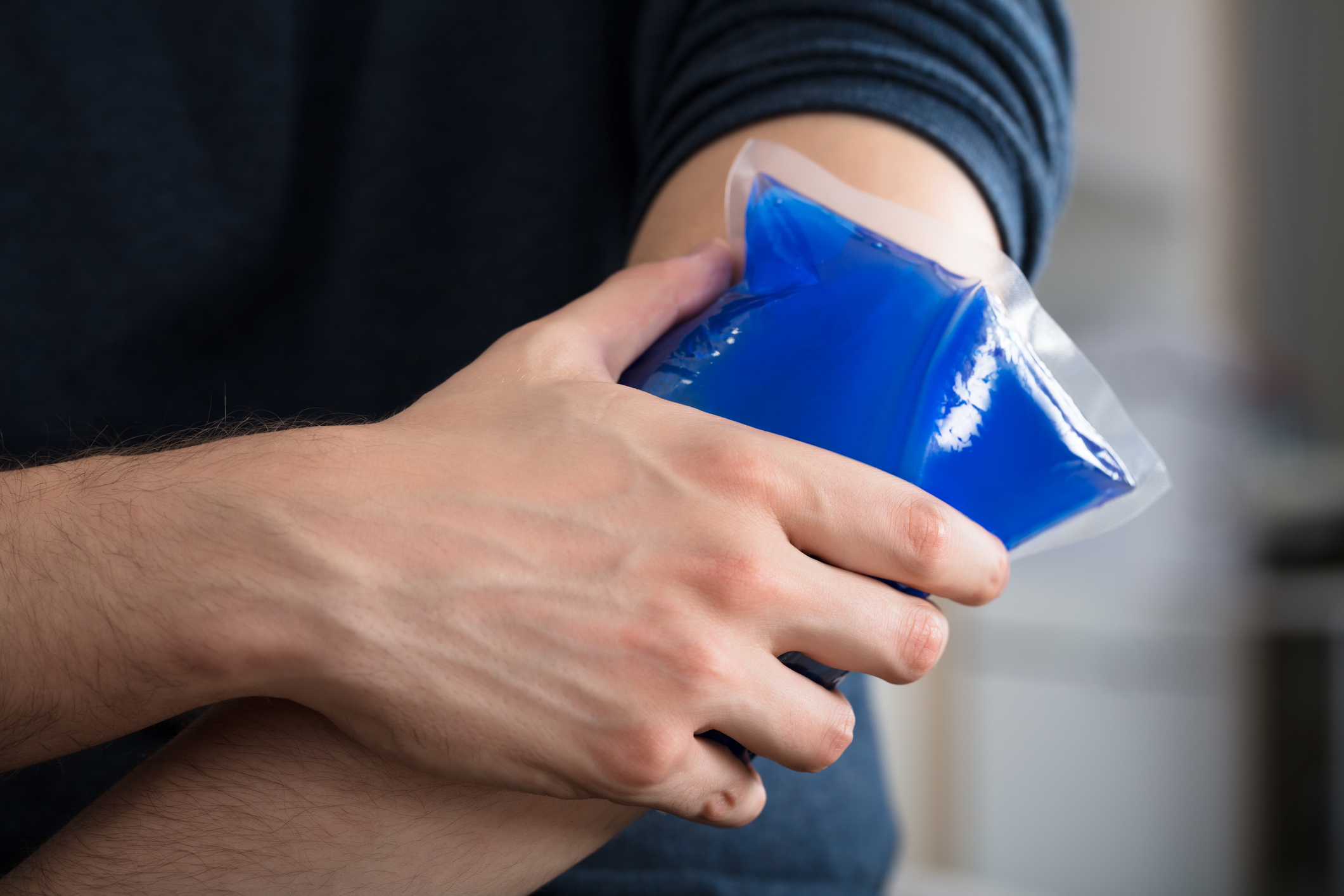 Person Applying Ice Gel Pack On An Injured Elbow Ice Gel Pack On An Injured Elbow